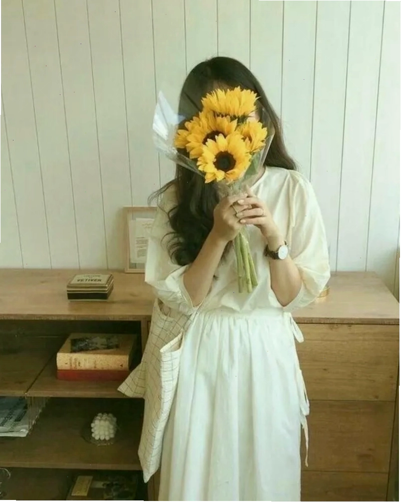Cô gái xinh đẹp che mặt bằng hoa hướng dương, mang lại năng lượng tích cực